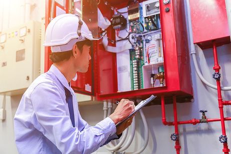Engineer inspecting a fire alarm control panel