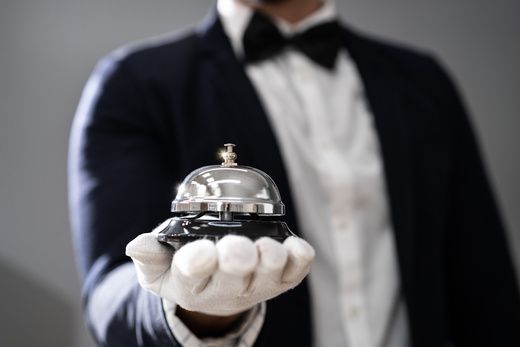 Concierge in white gloves holding a service bell